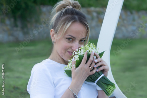 A young, beautiful girl with a bouquet of lilies of the valley on a walk.
