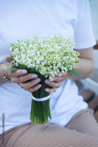 A young, beautiful girl with a bouquet of lilies of the valley on a walk.