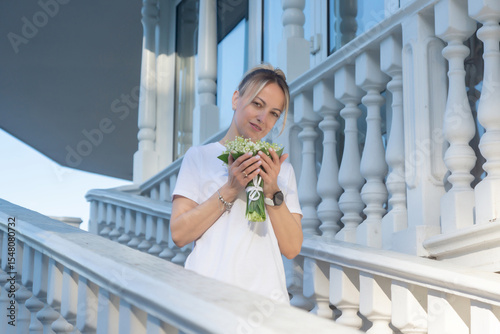 A young, beautiful girl with a bouquet of lilies of the valley on a walk.