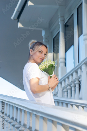 A young, beautiful girl with a bouquet of lilies of the valley on a walk.