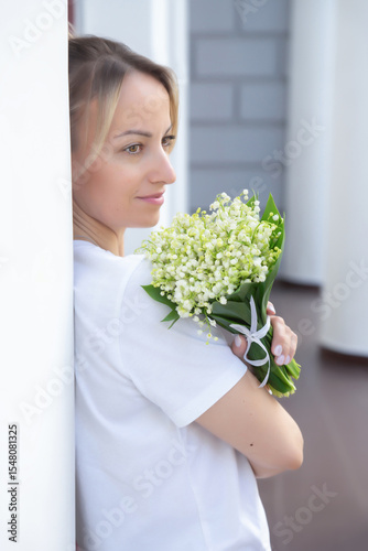 A young, beautiful girl with a bouquet of lilies of the valley on a walk.