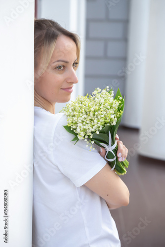 A young, beautiful girl with a bouquet of lilies of the valley on a walk.