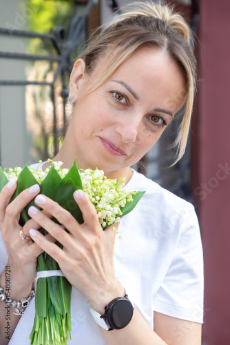 A young, beautiful girl with a bouquet of lilies of the valley on a walk.