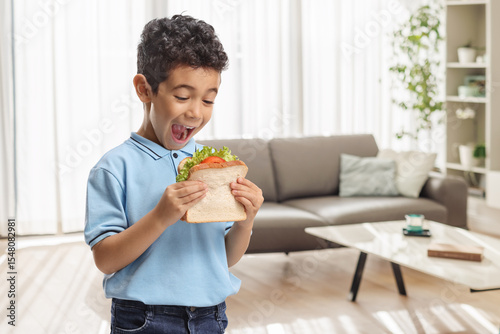 Overjoyed boy eating a tasty sandwich