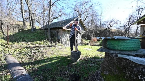 In a peaceful garden setting, a man focuses on carving wood with precision, enjoying the warmth of the sun and the serenity of nature around him.