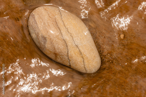 Lake Michigan washes over this lone stone along the beach at Kohler Andrae State Park, Sheboygan, Wisconsin