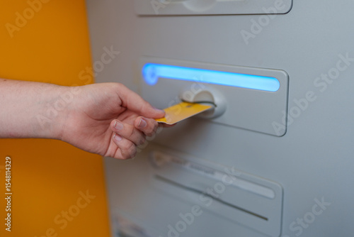 Obraz na plátně Yellow credit card being inserted into ATM machine, performing secure bank trans