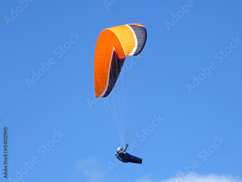 Paraglider flying in a blue sky	