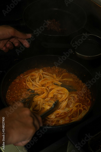 Chef cooking classic Italian linguine Bolognese in a professional restaurant kitchen – authentic cuisine, fresh ingredients, culinary art in action.