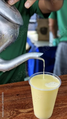 A close-up of someone pouring a refreshing  sugar cane juice, garapa, beverage from a pitcher into a glass.
