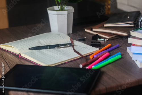For educational purposes, several colored markers and notebooks are on the wooden table.