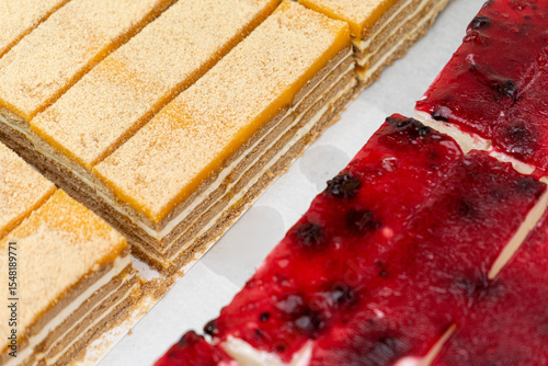 Slices of classic Portuguese bolo de bolacha and creamy strawberry cheesecake on a white plate, showcasing delicious layered desserts with rich textures and vibrant colors.