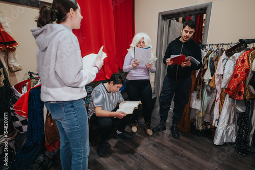 Fotografie A group of young thespians standing in a dressing room filled with costumes, deeply engaged in script rehearsal and preparing for an upcoming performance