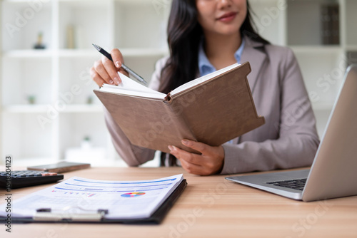 A young woman records information in a thick notebook.
