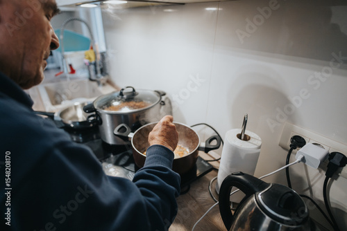 A scene of someone using a stove top to prepare a meal in a modern kitchen with various cookware, utensils, and appliances visible in a warm and homely setting.