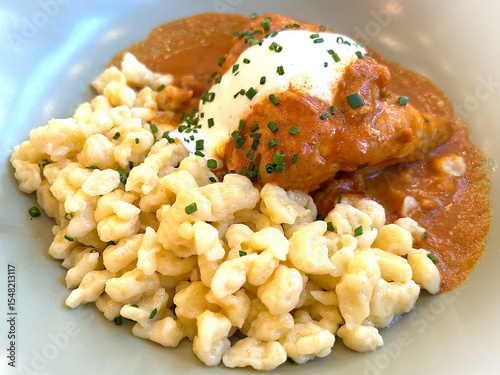 Austrian Paprikahendl served with soft homemade Nockerl (Austrian dumplings), topped with creamy sour cream and freshly chopped chives. A hearty and flavorful traditional dish, perfect for showcasing 