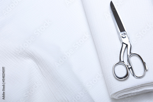 Elegant close-up of white 100% cotton fabric with metallic sewing scissors—ideal stock image for tailoring, sewing, textile design, and DIY projects. High-res craft and fabric concept.
