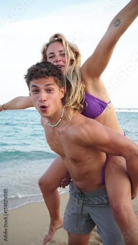 A cheerful young couple enjoying a delightful moment of joy and laughter while having fun at the beautiful beach coastline under the clear sky, creating lasting memories together by the sea.