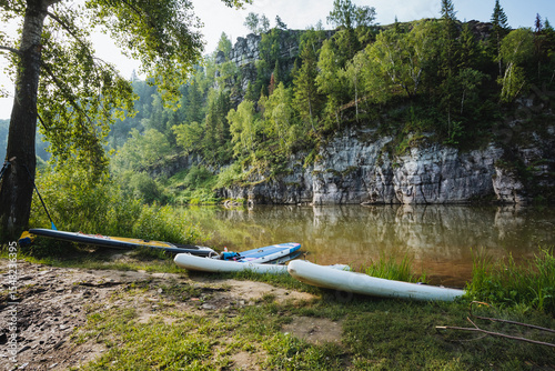 Wallpaper Mural A couple of colorful kayaks are sitting peacefully on the sandy shore of a beautiful river, awaiting adventurous paddlers to enjoy a captivating journey on the water surface Torontodigital.ca