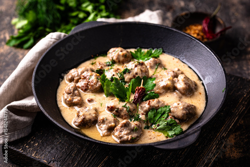 Meatballs in sour cream sauce in a frying pan