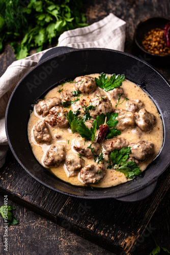 Meatballs in sour cream sauce in a frying pan