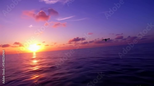 Aerial view of drone flying above sea at sunset with colorful sky reflecting off the water