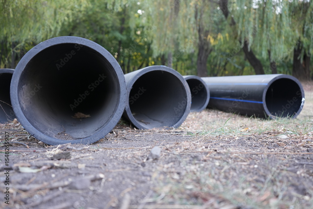Large black plastic pipes lying on the ground, prepared for installation in construction. High quality photo Large black plastic pipes lying on the ground, prepared for installation in construction. High quality photo
