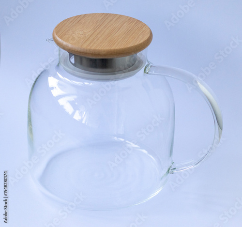 Stylish transparent tea pot with wooden lid on white background. Household items