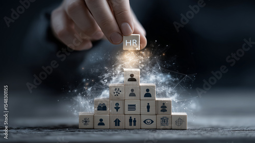Hand places final block atop triangle of wood figures, glowing icons above for HR traits