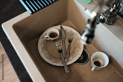 Dirty dishes, forks, and cups in a kitchen sink after a meal. Realistic scene of everyday home life and kitchen routine. Top view