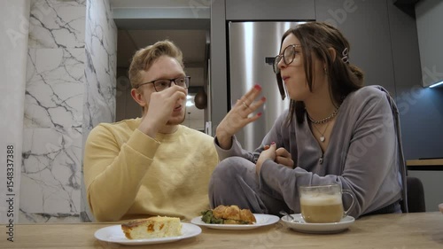 Cozy dinner at home, loving couple wearing glasses share delicious food and joyful laughter, demonstrating their deep connection in a beautifully decorated kitchen setting, perfect evening together