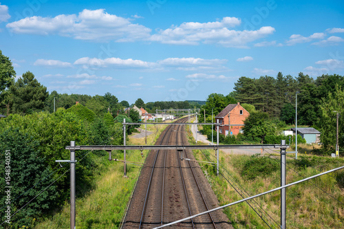 Railway tracks trough the green landscape and houses in Langdorp, Aarschot, Belgium