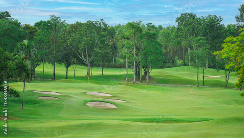 Fototapeta Naklejka Na Ścianę i Meble -  Lush Green Golf Course under Blue Sky with Palm Tree Lining.