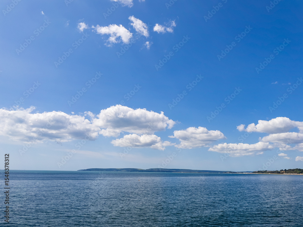 Fototapeta premium Bournemouth, UK - June 2nd 2025: Blue sky and clouds above Poole Bay.