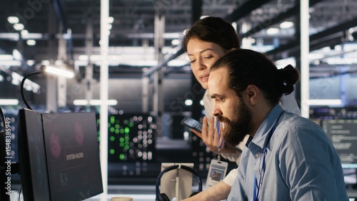 Anxious technicians in data center reacting to system lockdown caused by ransomware alert. IT professionals under pressure evaluating security breaches and scrambling to contain damage, camera A