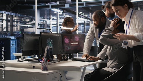 Scared data center technicians reacting to virus warning on PC display, scrambling to launch emergency response protocol. Admins run around server room, urgently trying to fix hacked systems, camera A