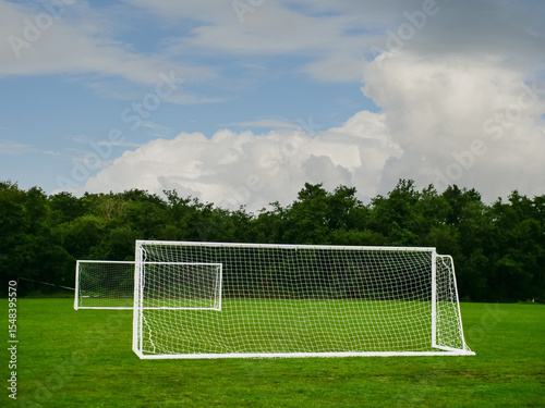 Clean cut football or soccer training ground with two goal posts, dark trees and dramatic sky in the background. Popular world sport. Team development area. Nobody.