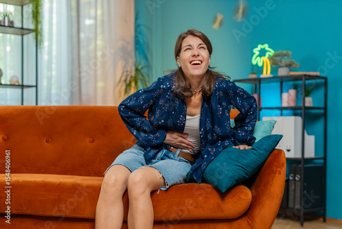 Фотография Sick ill Caucasian woman suffering from period cramps, painful stomach ache on sofa at home room