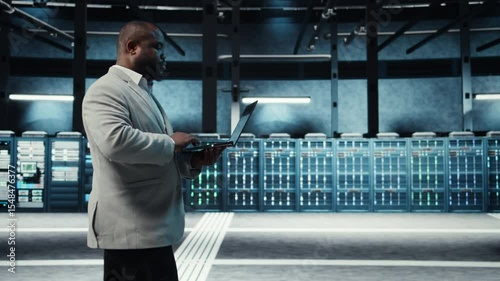 Software developer in data center using artificial intelligence tech on laptop to deploy new server architectures. IT expert in server hub updating storage arrays using AI technology, camera A