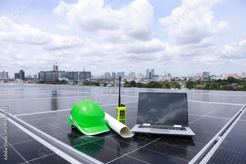 Green safety helmet or hard hat with drawing and laptop on solar panel, green renewable energy and sustainable energy concept 