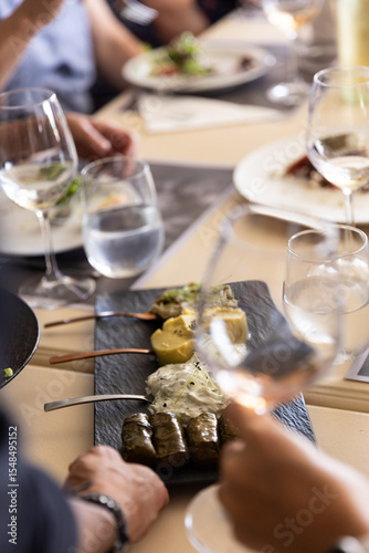 Platter of Greek appetizers being placed on a table where a group is enjoying wine during lunch.