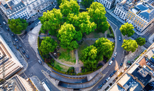 Aerial view of Cavendish Square Gardens in London surrounded by classic architecture, roads, and vehicles on a bright summer day.