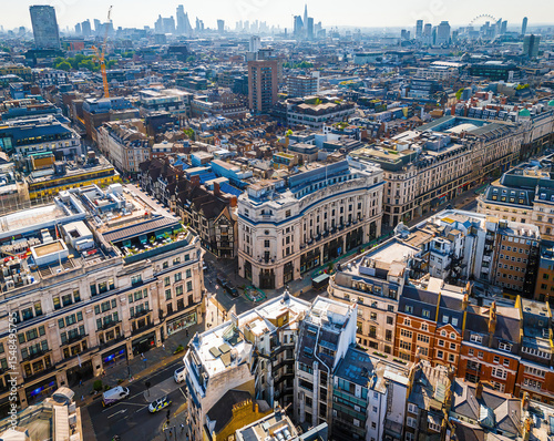 Aerial view of Regent Street in London with its sweeping curve, elegant architecture, red buses, and busy city streets on a clear day.