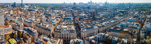 Aerial view of Regent Street in London with its sweeping curve, elegant architecture, red buses, and busy city streets on a clear day.
