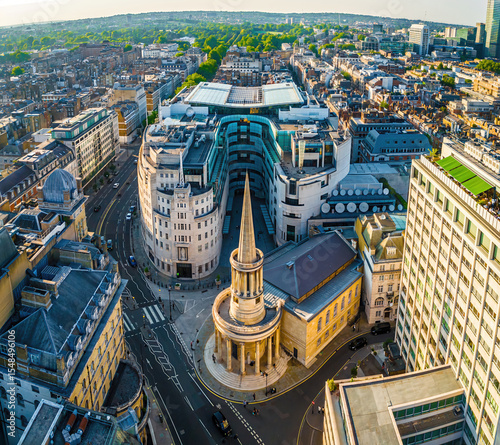 Aerial view of BBC Broadcasting House in London with the iconic All Souls Church and surrounding cityscape on a bright, clear day.