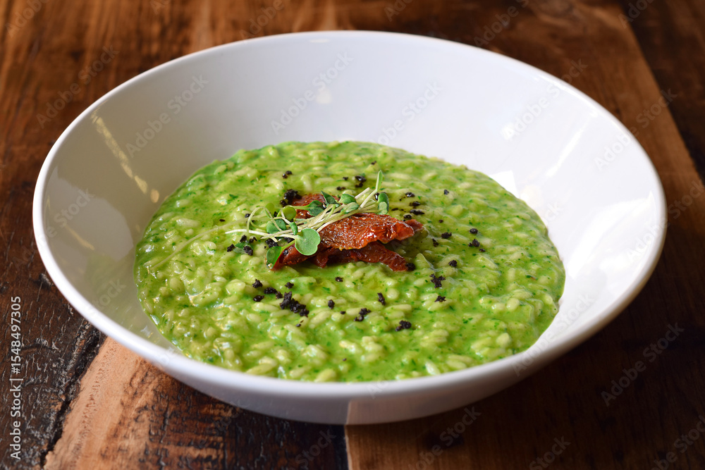 White bowl with green spinach risotto garnished with sundried tomatoes White bowl with green spinach risotto garnished with sundried tomatoes