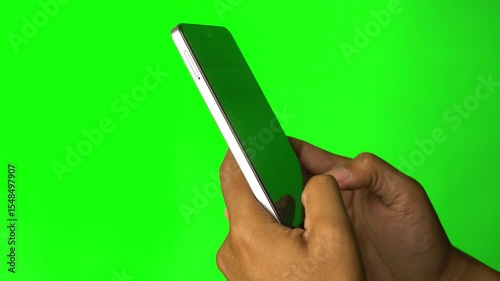 Hand holding smartphone and fingers typing on screen. Green background