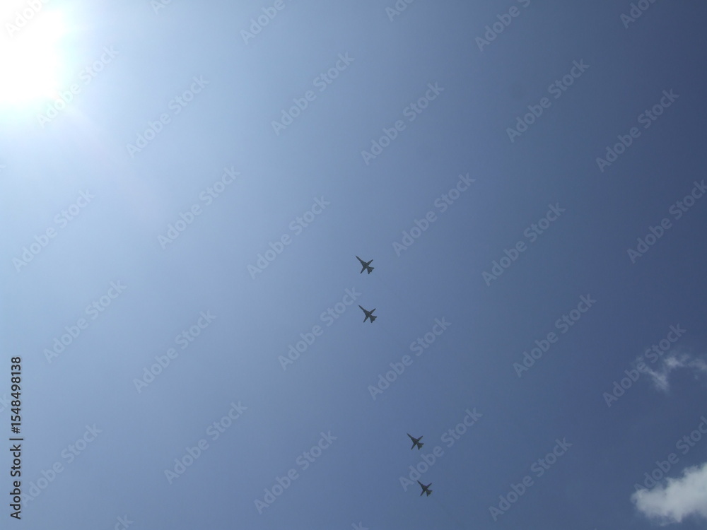 Obraz premium Four aircraft flying in a clear blue sky, with bright sunlight illuminating the scene, showcasing aviation in action and the beauty of flight dynamics