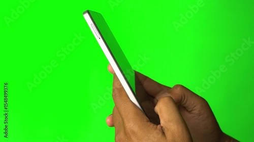 Hand holding smartphone and fingers typing on screen. Green background