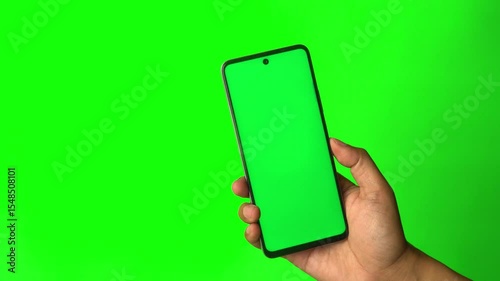 Hand holding smartphone with chroma green screen, finger tapping the screen. Green background